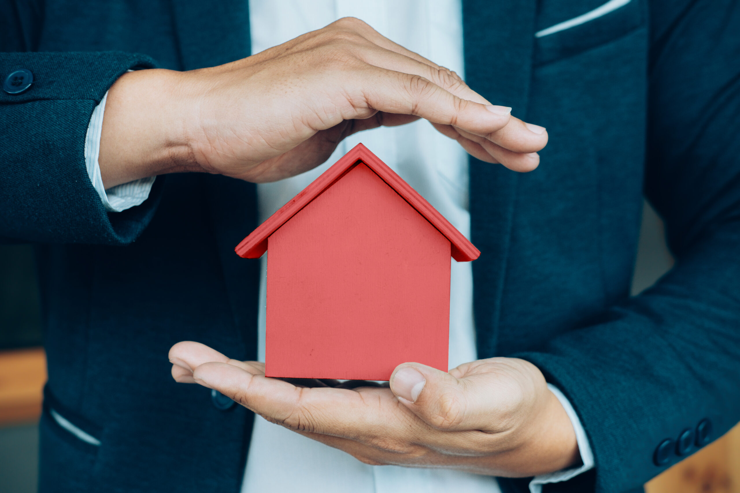 Business man hand hold the house model saving small house. Business man hand hold the house model saving small house. House insurance